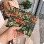 Astuccio realizzato in tessuto stampato con bacche rosse e nere e foglie verde scuro