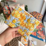 Astuccio realizzato in tessuto con fiori sui toni del giallo e del bianco