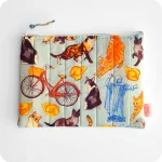 Astuccio realizzato in tessuto con gatti, cappelletti, coppie di pane e altri elementi legati a Ferrara (castello, biciclette, duomo, statua Savonarola) su sfondo azzurro