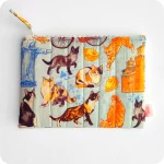 Astuccio realizzato in tessuto con gatti, cappelletti, coppie di pane e altri elementi legati a Ferrara (castello, biciclette, duomo, statua Savonarola) su sfondo azzurro