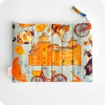 Astuccio realizzato in tessuto con gatti, cappelletti, coppie di pane e altri elementi legati a Ferrara (castello, biciclette, duomo, statua Savonarola) su sfondo azzurro