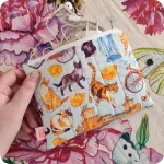 Astuccio realizzato in tessuto con gatti, cappelletti e altri elementi legati a Ferrara su sfondo azzurro