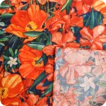 Dettaglio dell'orlo di una bandana realizzata con un tessuto in cotone stampato con fiori di papavero, oleandro e bouganville arancioni, fiori di gelsomino bianchi e foglie verde-blu