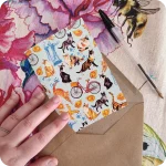 Biglietto d'auguri con gatti che saltano, biciclette, cappelletti, coppie di pane e statua del Savonarola su fondo azzurro