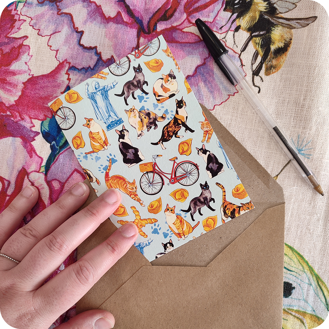 Biglietto d'auguri con gatti che saltano, biciclette, cappelletti, coppie di pane e statua del Savonarola su fondo azzurro