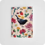 Fronte di un biglietto di auguri decorato con un merlo al centro attorniato da fiori, fragole, coccinelle, api su un fondo rosa