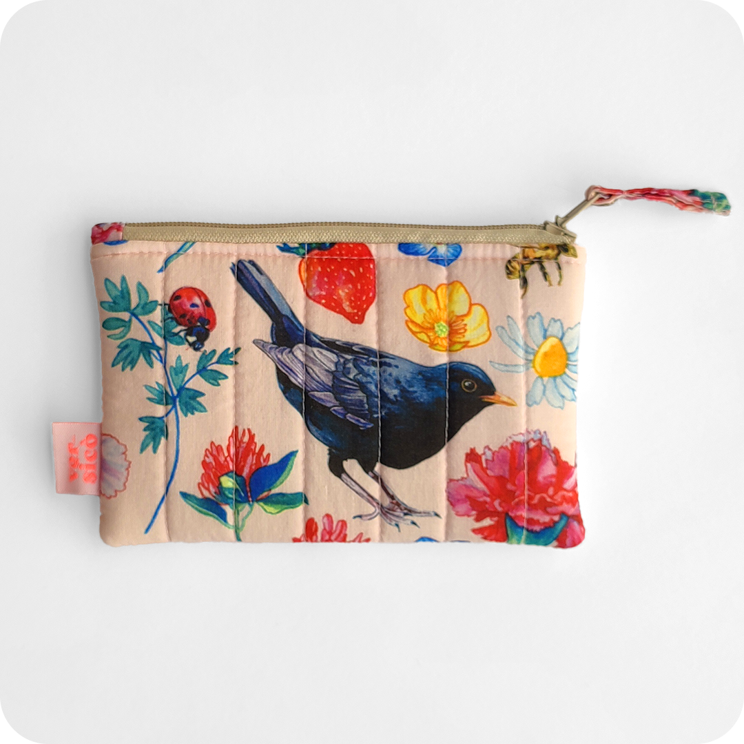 Borsellino realizzato con un tessuto stampato con un merlo al centro e attorno coccinelle, api, fiori, fragole e foglie su sfondo rosato