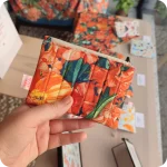 Borsellino realizzato con tessuto stampato con fiori di papavero, oleandro e bouganville sui toni dell'arancione e foglie dal colore bluastro