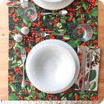 Runner apparecchiato realizzato con un tessuto stampato con una fitta fantasia di bacche e foglie, con tovagliolo in lino con la fantasia dei pettirossi