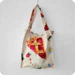 Borsa in tessuto stampato con una fantasia con fette di crostata, formiche, fiori e fragole su fondo chiaro
