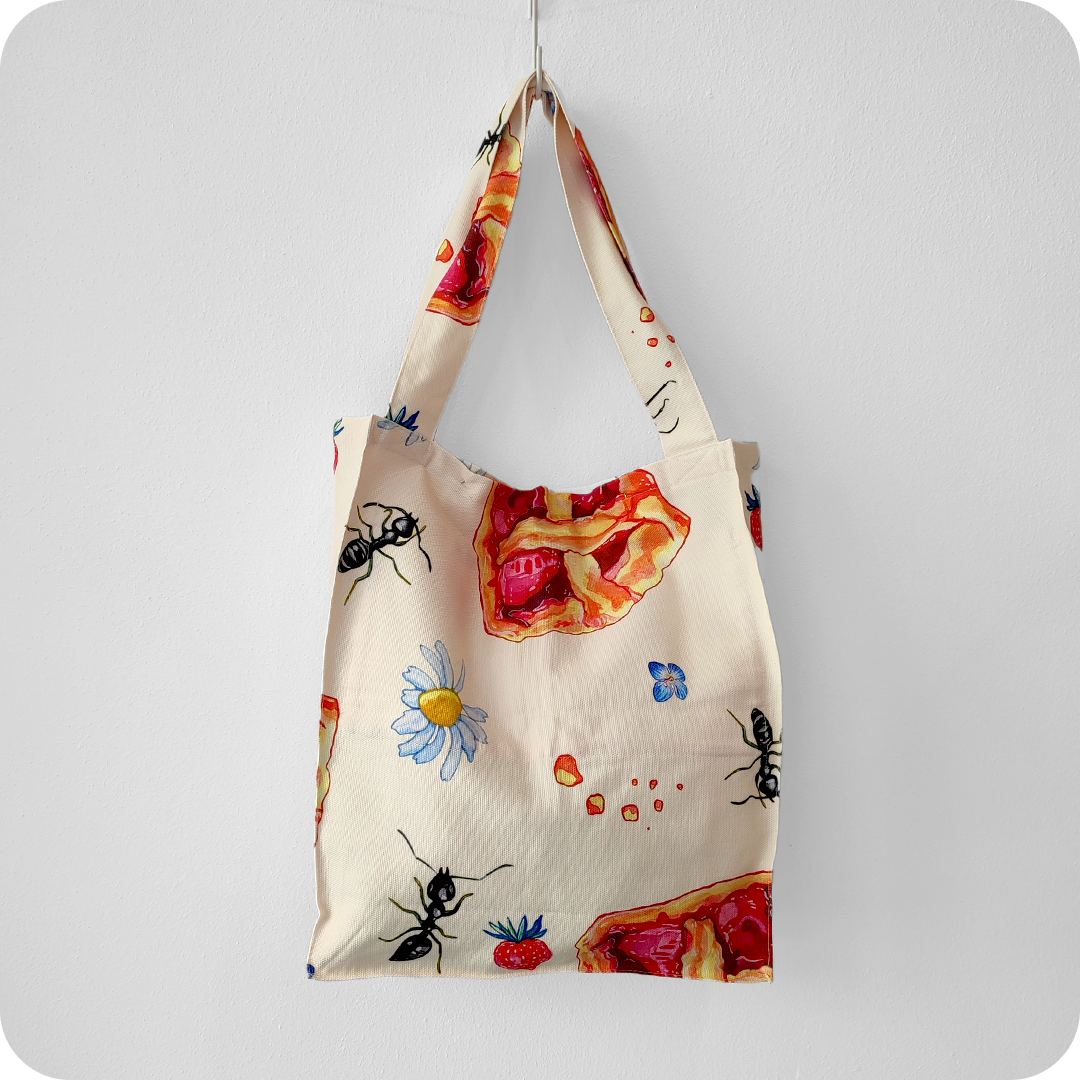 Borsa in tessuto stampato con una fantasia con fette di crostata, formiche, fiori e fragole su fondo chiaro