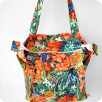 Borsa con cerniera in tessuto stampato con una fantasia jungle con pappagalli e falene che sbucano tra fiori e foglie