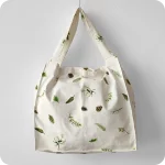 Grande borsa in tessuto stampato con un motivo con rametti di pino, bacche e pigne su fondo bianco