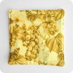 Sottopentola in tessuto imbottito realizzato con una stoffa stampata con grappoli d'uva, farfalle e rose canine sui toni del giallo