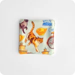 Fronte di un sottotazza con gatti e un cappelletto su fondo azzurro