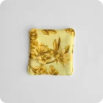 Fronte di un sottotazza con al centro delle rose canine su fondo giallo