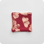 Fronte di un sottotazza con al centro una farfalla chiara su fondo rosso scuro