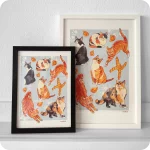 Due stampe incorniciate che raffigurano sei gatti diversi in varie posizioni, a scopo decorativo sono presenti tortellini e una coppia di pane