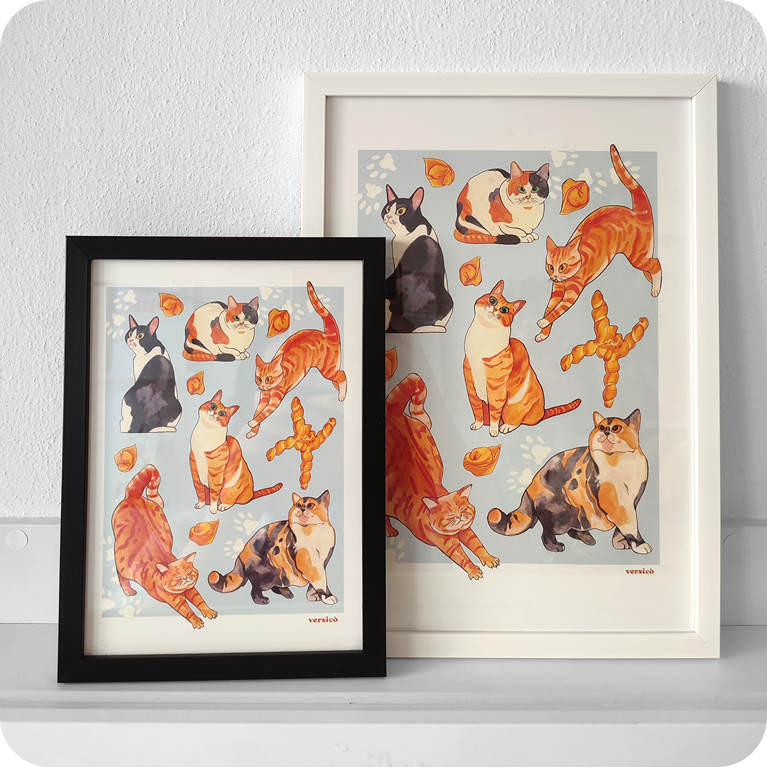 Due stampe incorniciate che raffigurano sei gatti diversi in varie posizioni, a scopo decorativo sono presenti tortellini e una coppia di pane