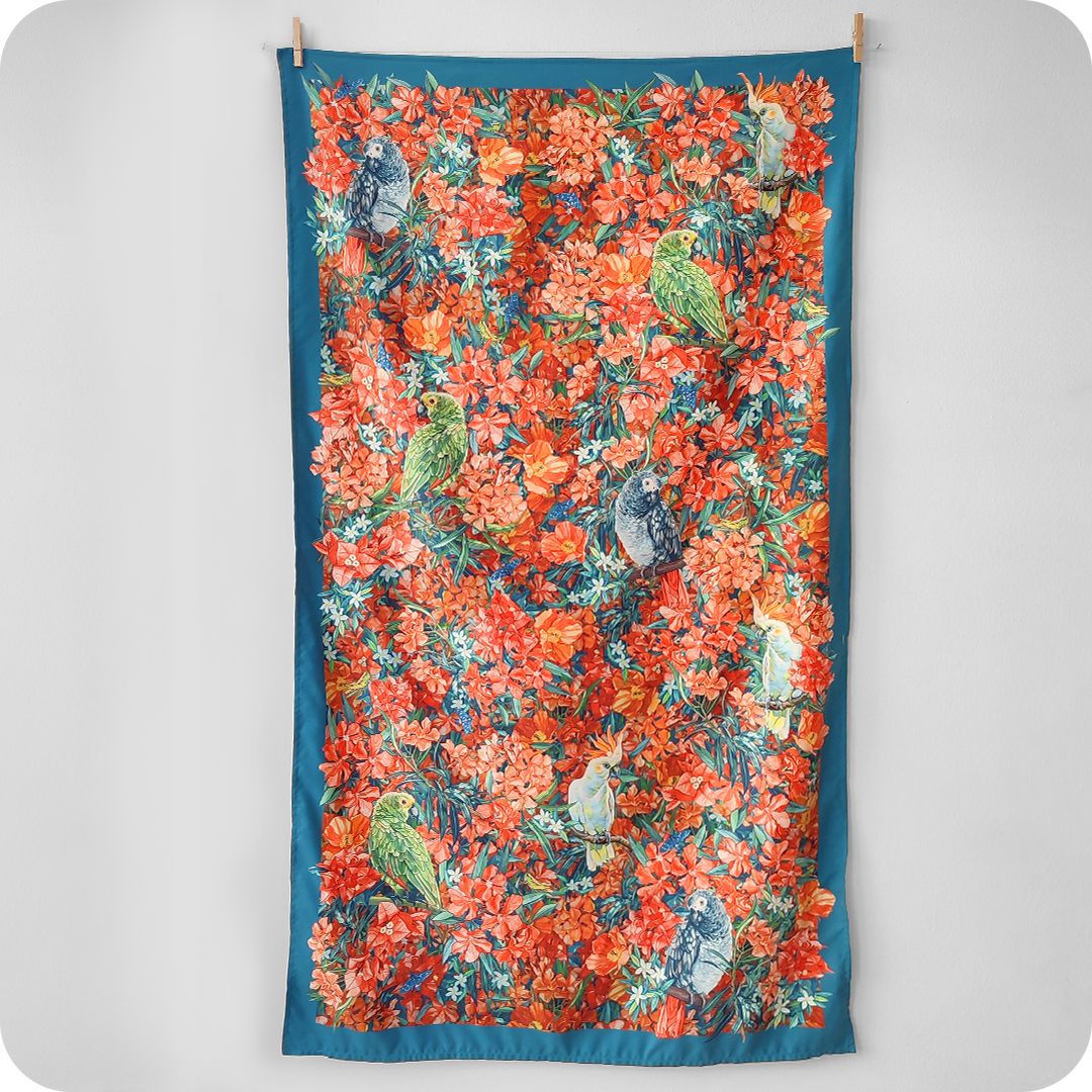 Telo mare appeso realizzato con un decoro centrato con pappagalli e fiori e una cornice blu