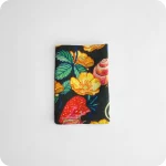 Tovagliolo piegato in tessuto stampato con una fantasia di chiocciole, coccinelle, fragole e fiori su fondo scuro