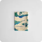 Tovagliolo piegato in tessuto stampato con una fantasia di foglie verdi azzurre su fondo chiaro