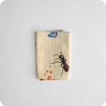 Tovagliolo piegato in tessuto stampato con una fantasia di fette di crostata, formiche, fiori e fragole