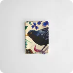 Tovagliolo piegato in tessuto stampato con una fantasia di merli, passerotti, lombrichi, fiori e foglie su fondo chiaro