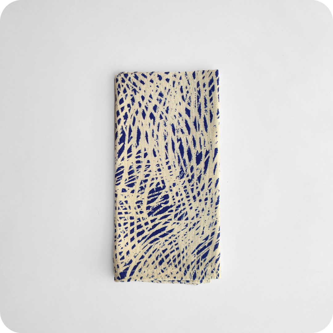 Tovagliolo piegato in tessuto stampato con una fantasia di tratteggi bianchi su fondo blu