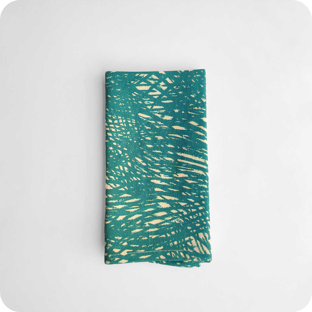 Tovagliolo piegato in tessuto stampato con una fantasia di tratteggi verdi su fondo chiaro