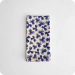 Tovagliolo piegato in tessuto stampato con una fantasia di trifogli blu su fondo chiaro