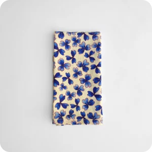 Tovagliolo piegato in tessuto stampato con una fantasia di trifogli blu su fondo chiaro