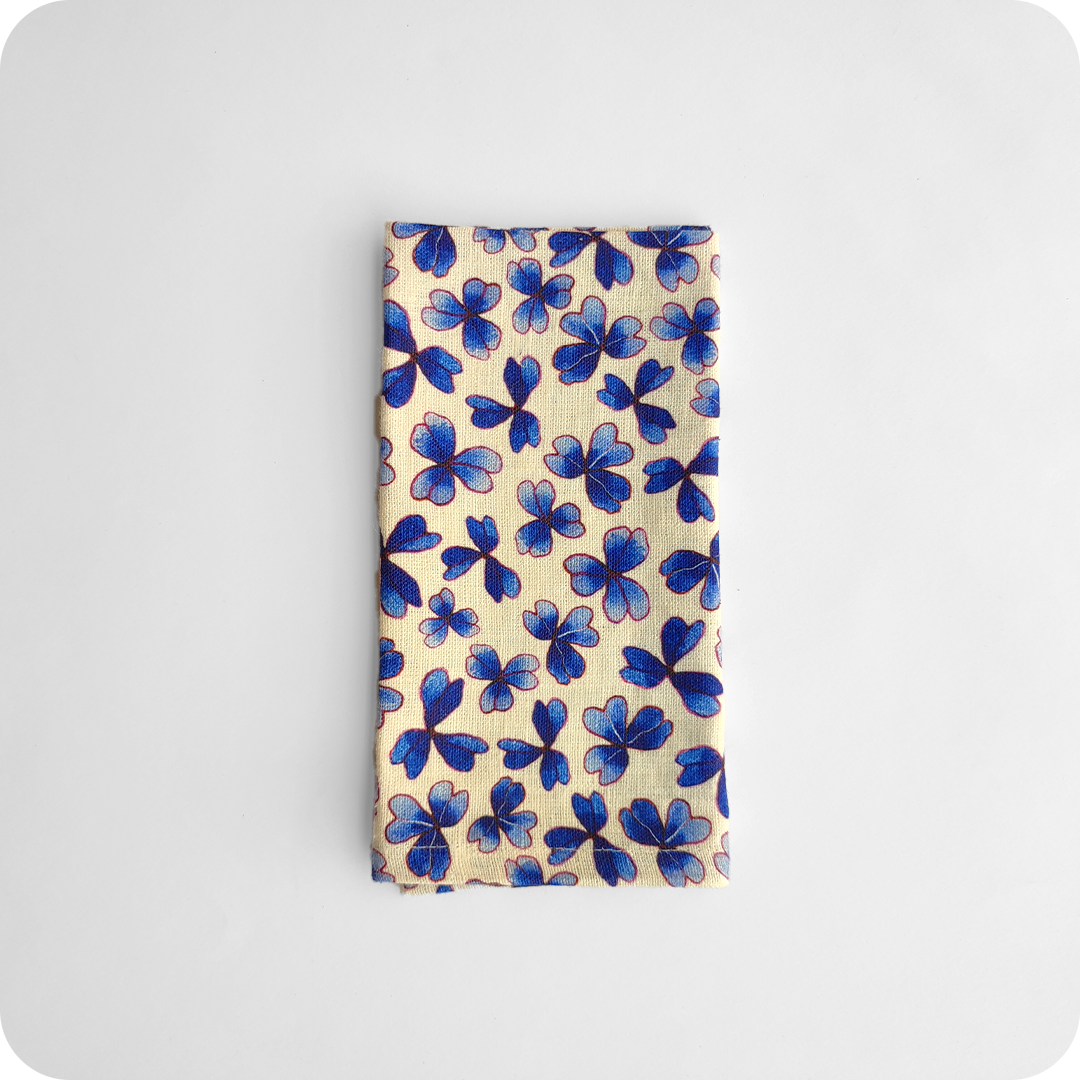 Tovagliolo piegato in tessuto stampato con una fantasia di trifogli blu su fondo chiaro