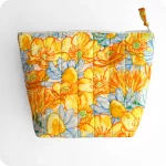 Trousse realizzata con un tessuto stampato con fiori gialli di ranuncolo selvatico e tarassaco, intervallati da fiori di camomilla e margherite bianche