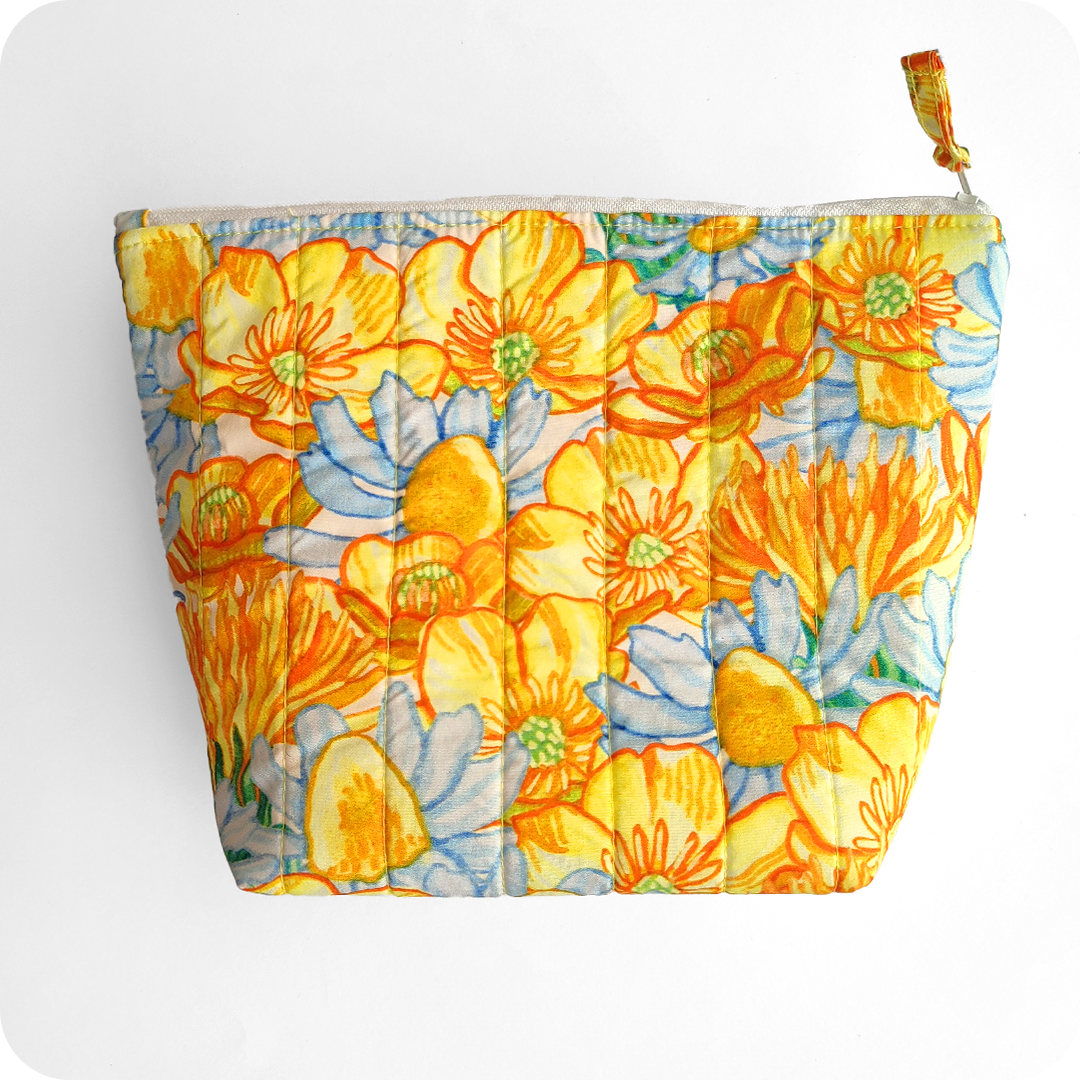 Trousse realizzata con un tessuto stampato con fiori gialli di ranuncolo selvatico e tarassaco, intervallati da fiori di camomilla e margherite bianche