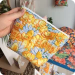 Trousse realizzata con un tessuto stampato con fiori gialli di ranuncolo selvatico e tarassaco, intervallati da fiori di camomilla e margherite bianche
