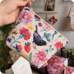 Una trousse realizzata con un tessuto stampato con merli, fiori, foglie, farfalle, coccinelle e api su fondo rosato